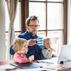 Middle aged man working at computer with two kids on his lap