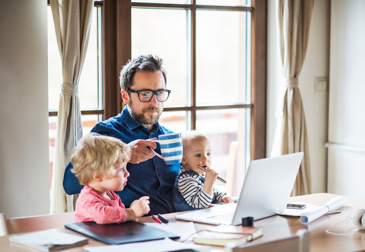 Middle aged man working at computer with two kids on his lap