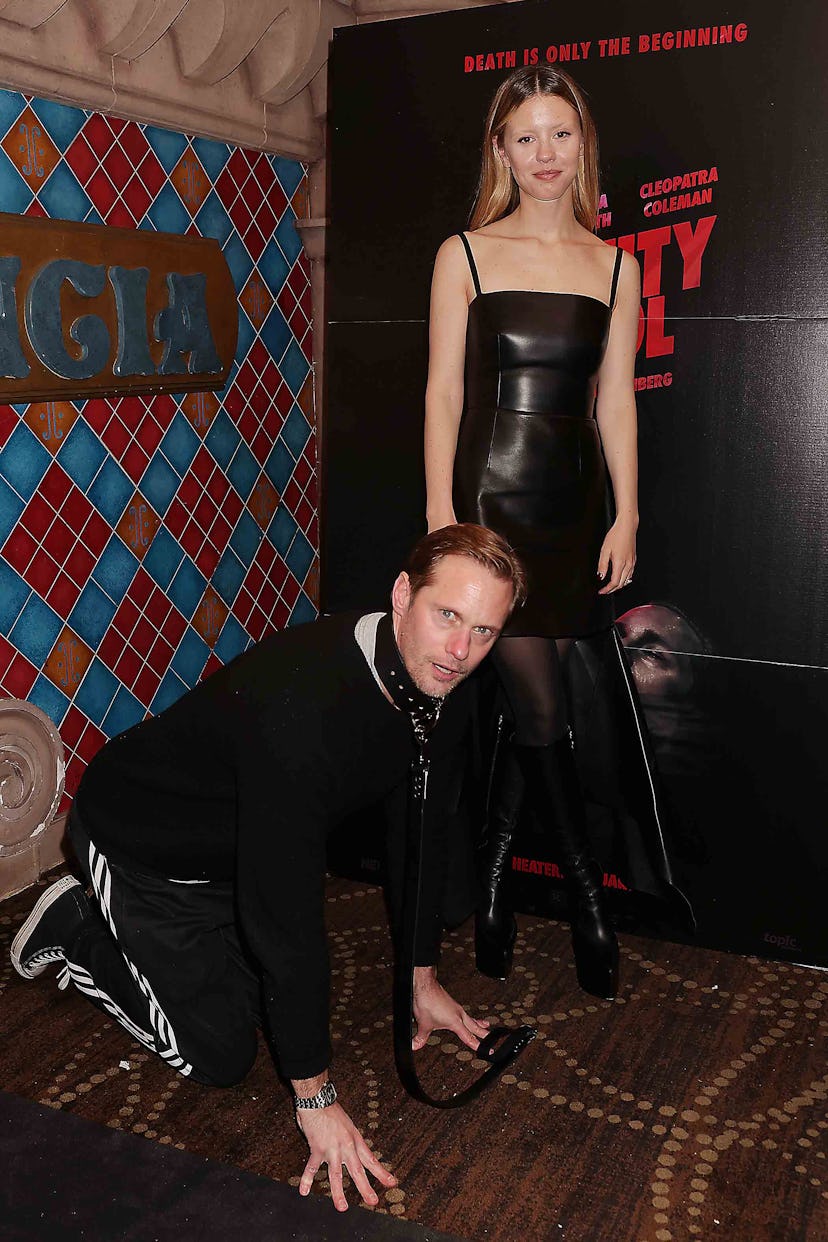 Alexander Skarsgard being walked on a leash by Mia Goth.
