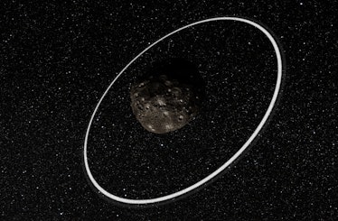 color image of a rocky asteroid encircled by thin white rings