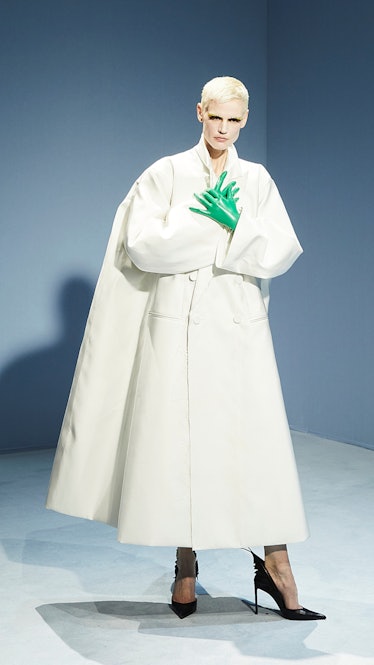 Model in white coat dress and green gloves