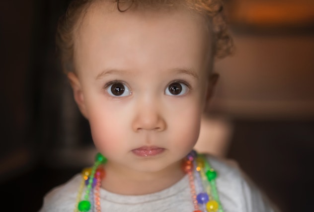 A mixed-race toddler looks directly at camera while in her home in article about baby girl names tha...