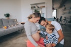爸爸和怀孕的妈妈坐在他们的宝宝身边，宝宝把手伸到妈妈的肚子上。