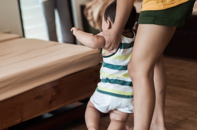 A mom helping her baby walk at home.