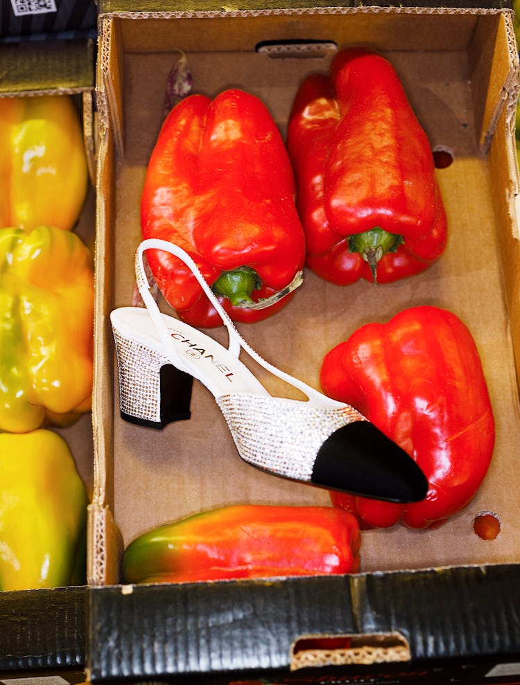 Chanel glitter black tip shoe in a box of red peppers.