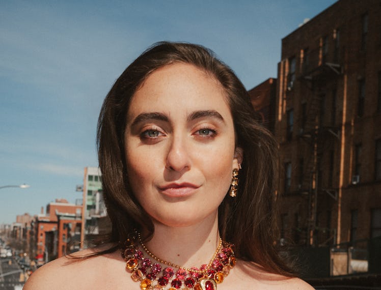 Catherine Cohen, a comedian, stares into the camera with a bemused expression. She's wearing a black...