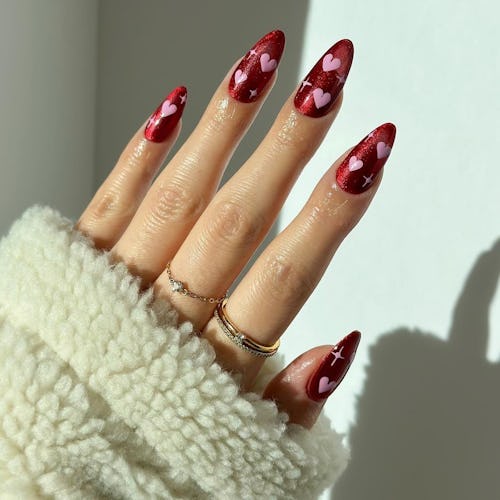 Red nails with pink hearts are a simple heart nail art design for Valentine's Day 2023.