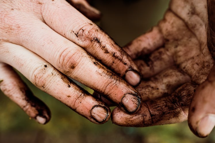 A woman's hands covered in dirt.