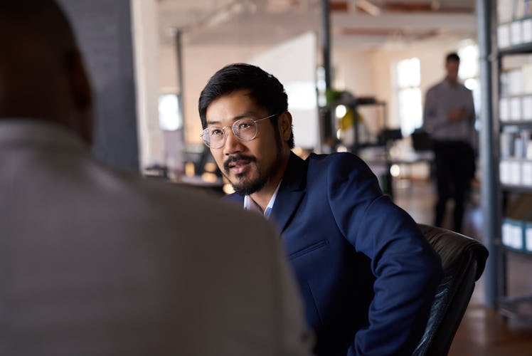 Man in glasses talking to boss in office setting
