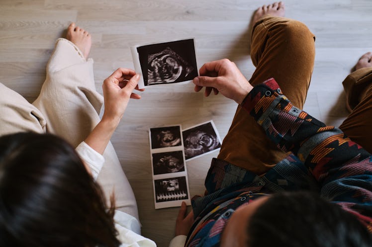 A man and a pregnant woman looking at ultrasounds of their baby.