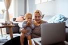 一个婴儿和他们的妈妈在家里的电脑上看视频。