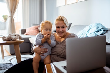 A baby and their mom watch a video on a computer at home.