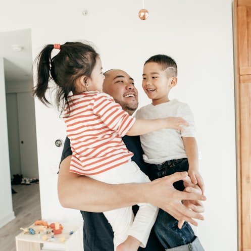 一位父亲抱着他的两个孩子，面带微笑。