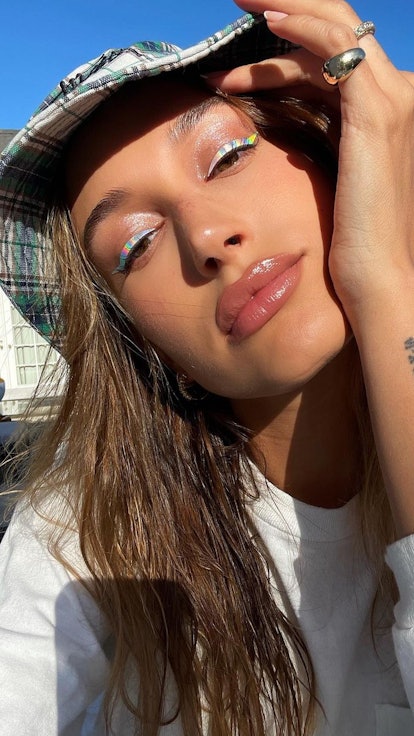 Hailey Bieber numeral wrist tattoo with bucket hat and holographic eyeliner