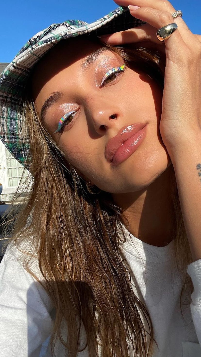 Hailey Bieber numeral wrist tattoo with bucket hat and holographic eyeliner
