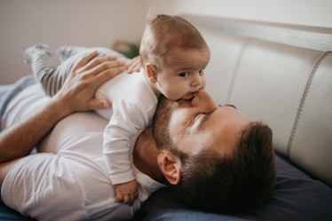 A dad lying on a couch with his baby on top of his chest.