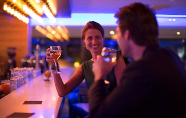 Man and woman drinking wine and flirting at a hotel bar