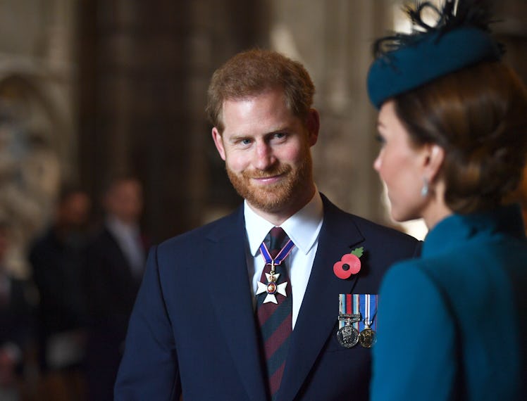 Prince Harry looks on at Kate Middleton. 