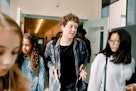 一个男孩和两个女孩走过学校的走廊。