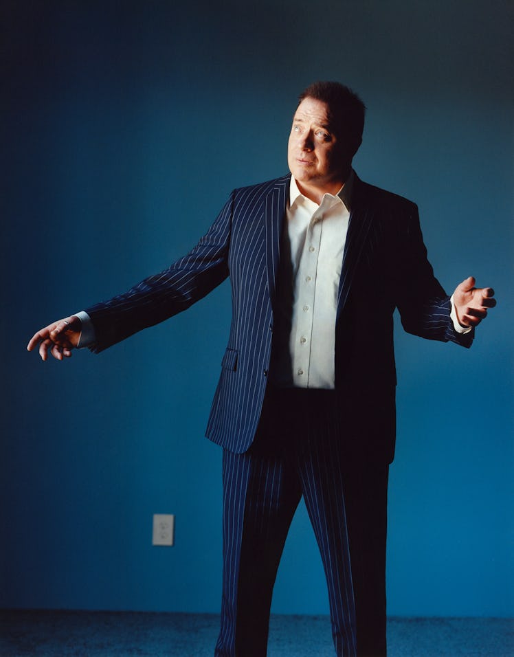 Brendan Fraser wears a navy blue pin-strip suit and button-down shirt.