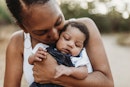 一个黑人妈妈抱着,亲吻她的宝宝。