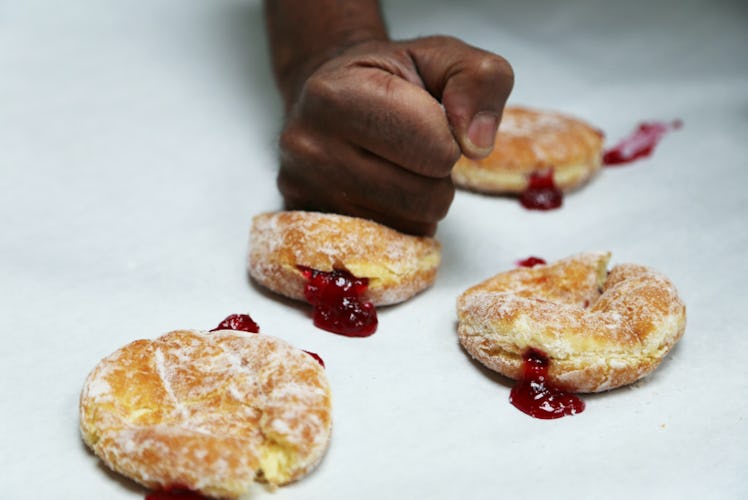 a person's fist squishing a jelly doughnut