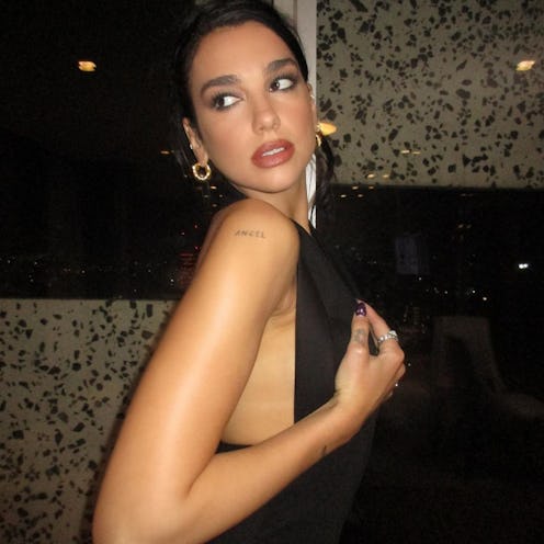 Dua Lipa side pose over shoulder with updo and tattoo