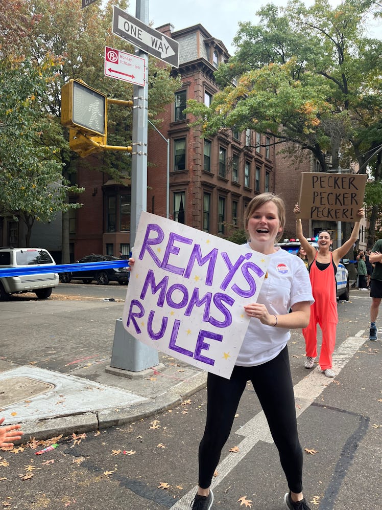 The writer's friend holding a sign that says "Remy's moms rule!"