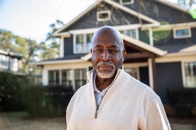 Man standing confidently in front of his home