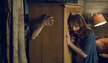 Dana Polk (Kristen Connolly) pushes a wardrobe against a monster in The Cabin in the Woods