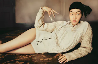 Model Kim wears white knit cable sweater, pearls and sweater shorts