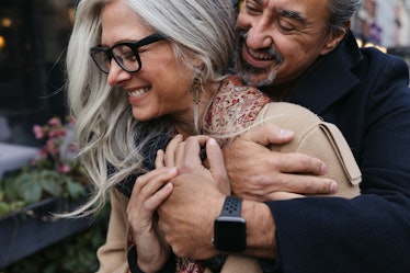 Stylish, older man and woman hugging outside