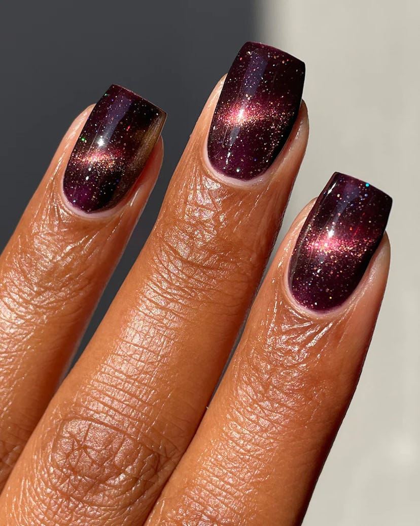 Dark red cat eye nails, created with magnetic nail polish, is one of fall 2023's most popular nail p...