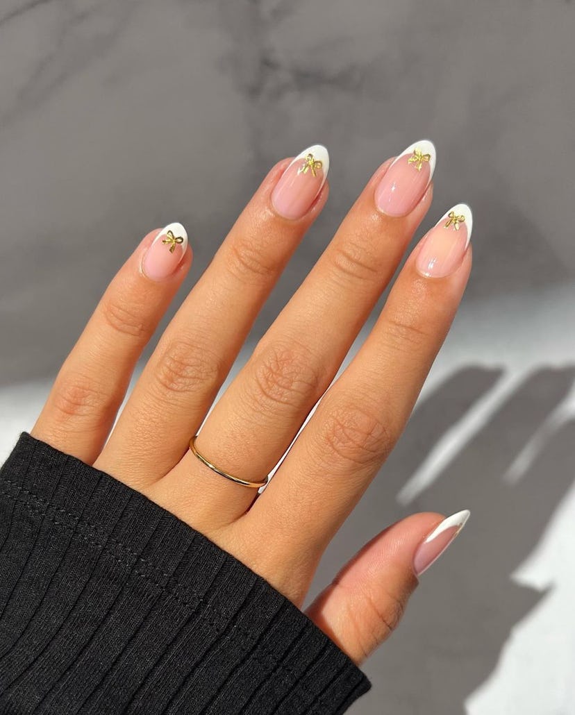 If you need manicure inspo, bow nail art on French tips is a minimal nail design for short nails tha...