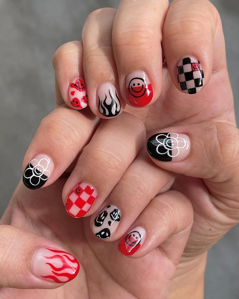 A trendy checkered nail design for 2023 that includes flame black nail art, smiley faces, and flower...