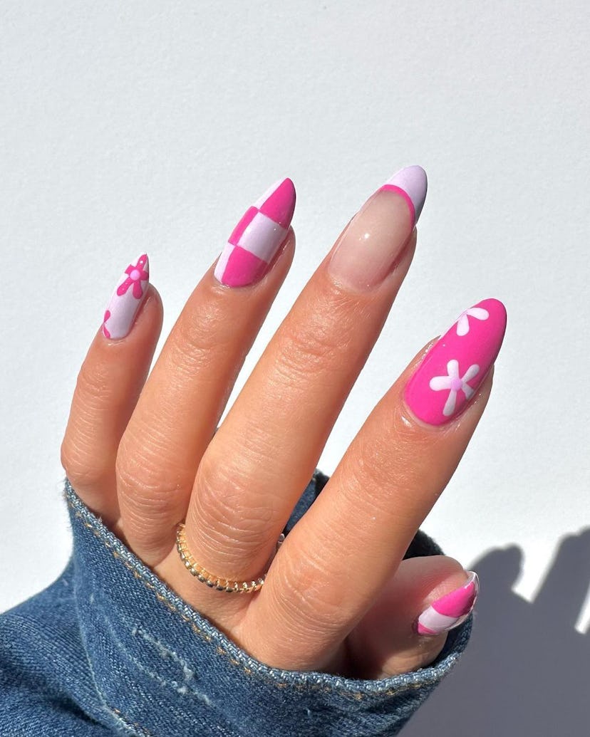 A cute pink nail art design for 2023 that combines checkered nails, French tips, and daisy nail art.