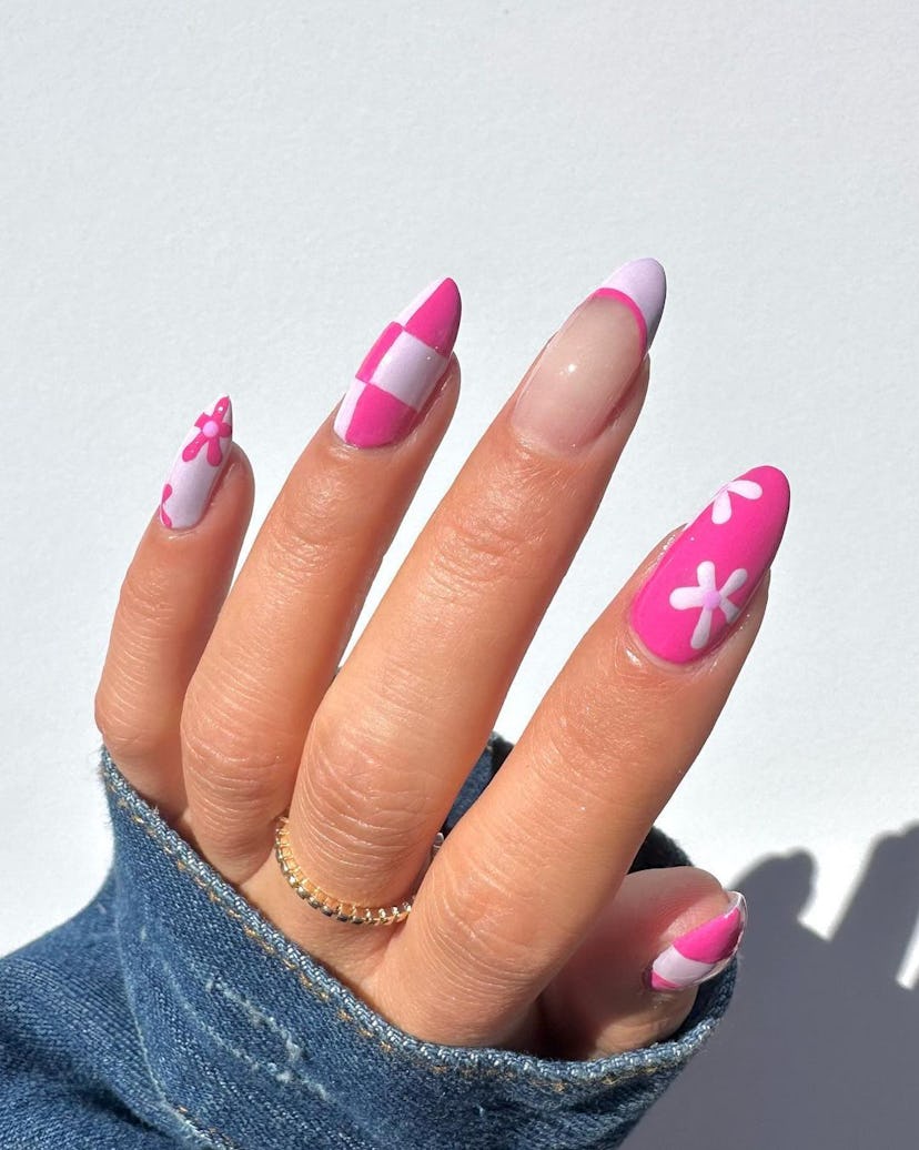 A cute pink nail art design for 2023 that combines checkered nails, French tips, and daisy nail art.