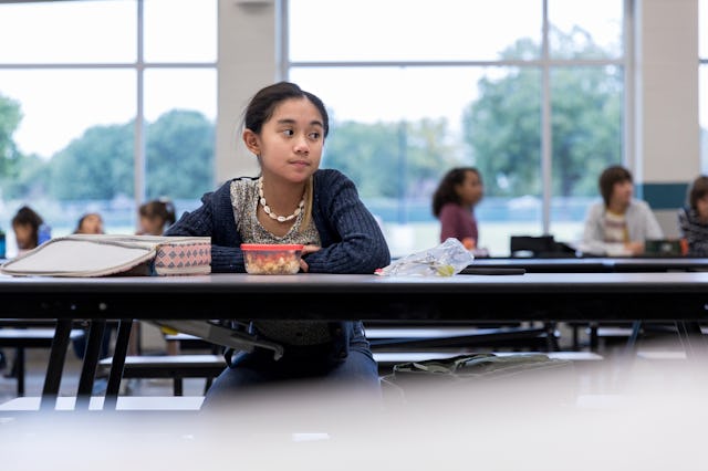 A lonely child sits in the cafeteria at school.