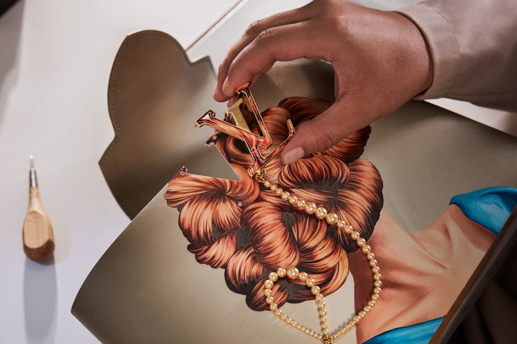 an artists hands finishing a Louis Vuitton bag