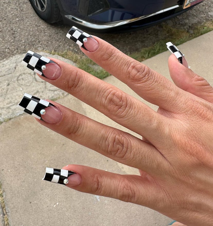 A trendy black & white nail art design for 2023 with checkered print French tips.