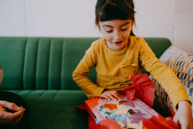 A child unwraps a gift at a birthday celebration.