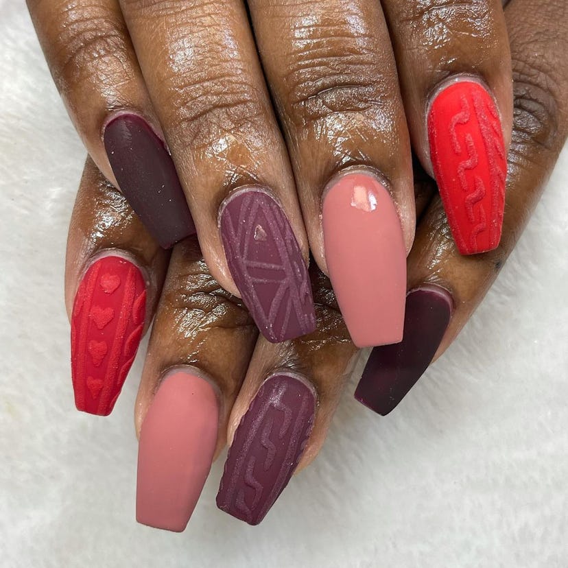 If you need a winter manicure design idea for 2023, these purple, mauve, and red sweater nails are o...