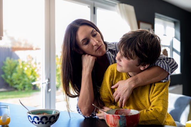 A mother holds her son close as they have a serious conversation.
