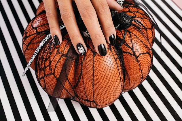 black nails with a white spider on the accent nail