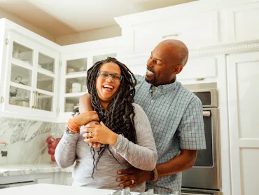 Happy couple in kitchen smiling and hugging