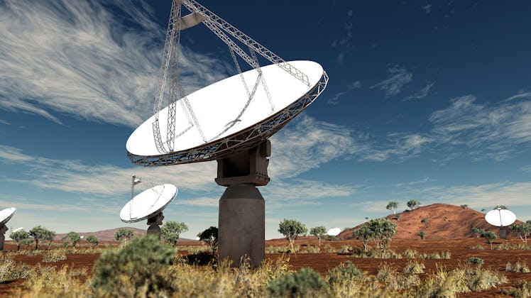 radio antenna dishes in a scrubby landscape under a blue sky