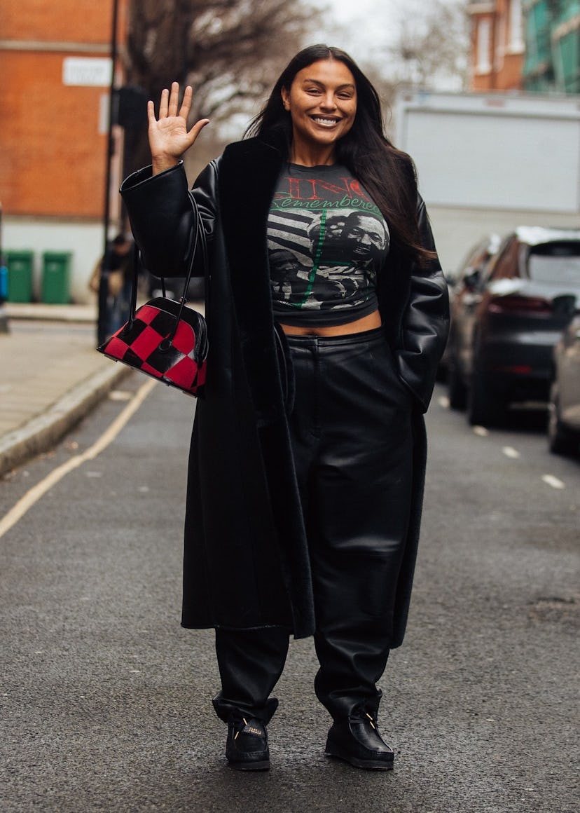 Model Paloma Elsesser waves and wears a black leather trench, black Martin Luther King Jr. shirt, bl...
