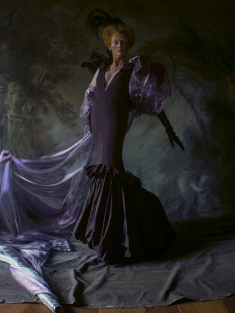 Tilda Swinton wears a violet gown and black hat.