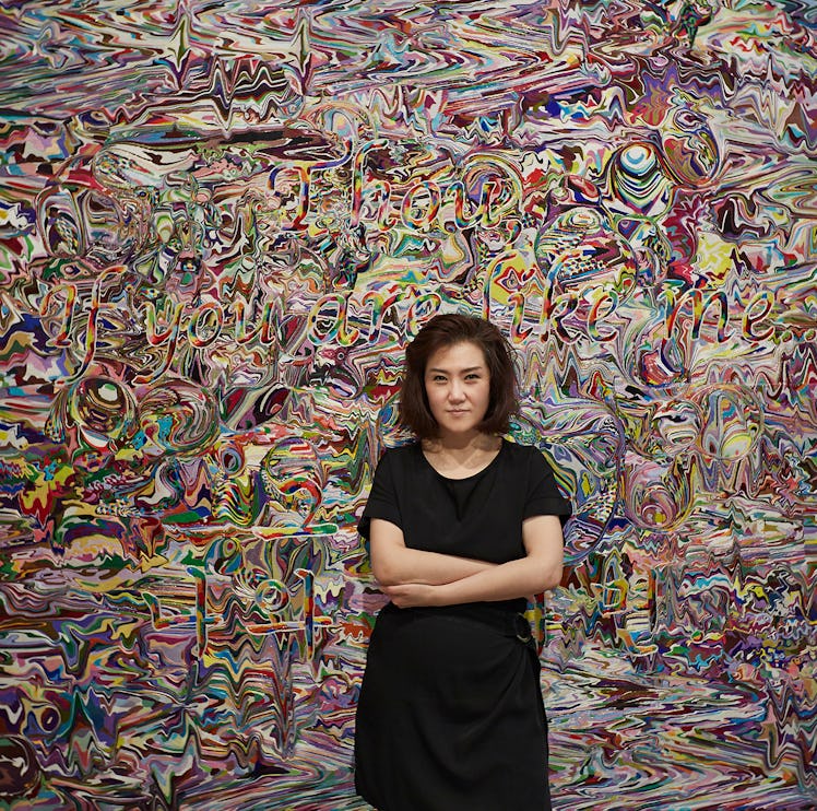 artist Kyungah Ham standing in front of Needling Whisper, Needle Country / SMS Series in Camouflage ...