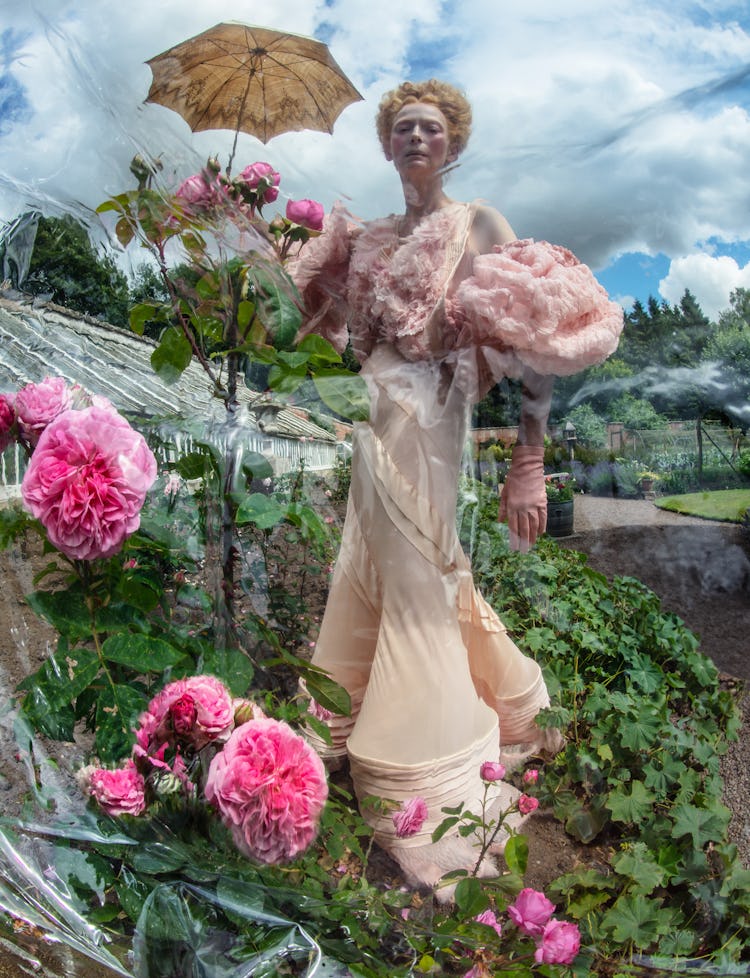 Tilda Swinton wears a cream dress, pink gloves and parasol.